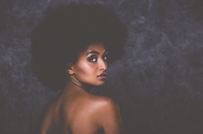 Portrait of beautiful young woman against wall