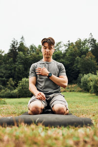 Young man doing exercises outside on grass during his calisthenics workout