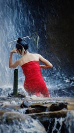 Rear view of woman splashing water in sea