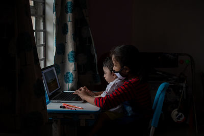 Rear view of child playing on laptop at home