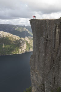 Hikers standing on edge of pulpit rock cliff by lysefjorden fjord, norway