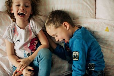 Brother and sister laughing. siblings having fun at home in bedroom