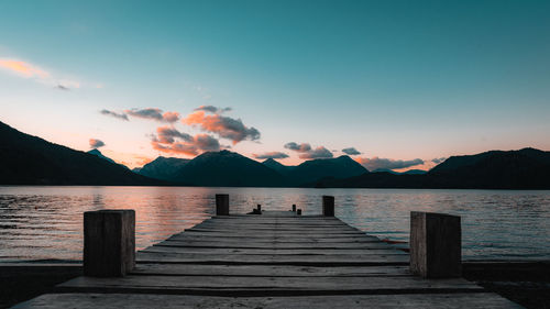 Pier over lake against sky during sunset