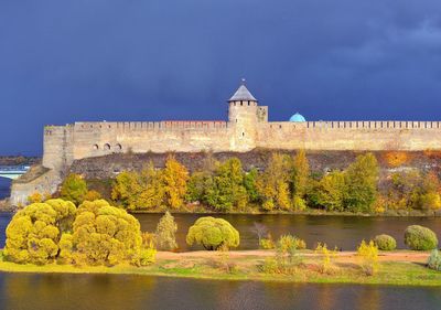 Historic building by river during autumn