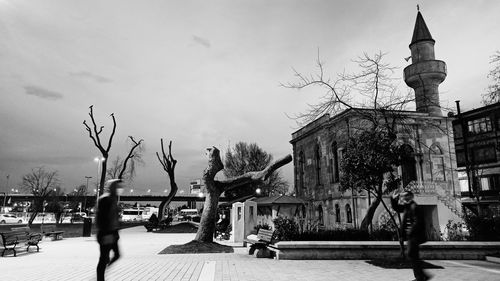 Statue on street by building against sky