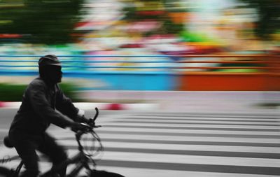 Blurred motion of man riding bicycle on street