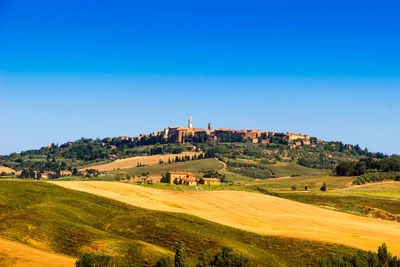 Scenic view of agricultural landscape against clear blue sky