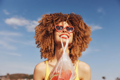 Portrait of young woman wearing sunglasses while standing against sky