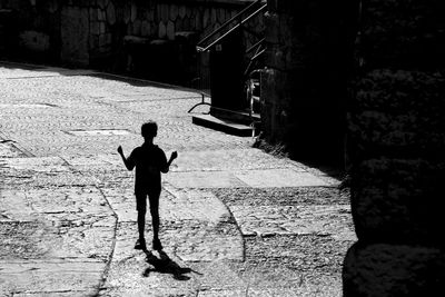 Rear view of boy standing on footpath