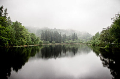 Scenic view of lake by trees against sky