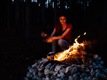 Young man sitting on log in forest