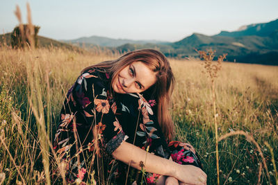 Portrait of beautiful woman sitting on field