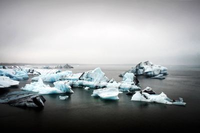 Glaciers in sea against clear sky