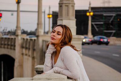 Young woman standing by retaining wall