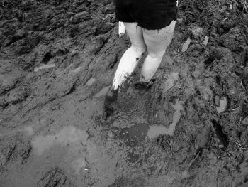 Low section of man standing on puddle at beach