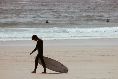 Man with surfboard walking on beach