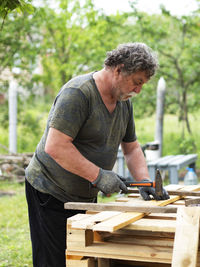 Man working on wood against trees