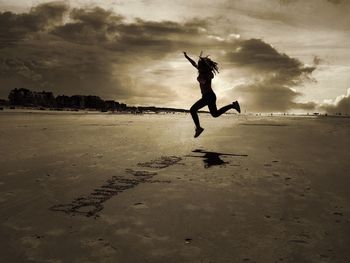 Silhouette of girl jumping on beach