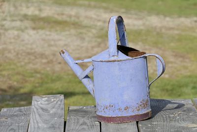 Close-up of old blue metal watering can  on field