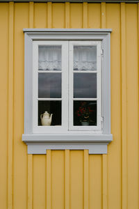 Kettle and plant in the window of a yellow painted house