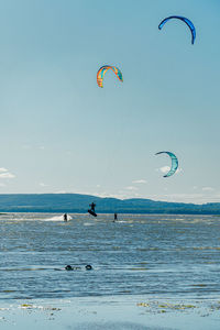 People enjoying at beach against sky