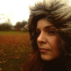 Close-up portrait of young woman looking away on field