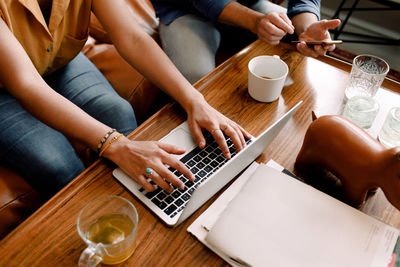 Midsection of female executive typing on laptop while sitting with colleague in office