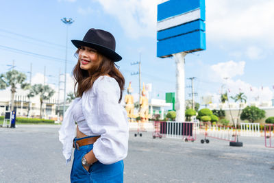 Young woman wearing hat standing in city