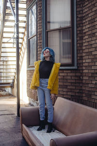 Portrait of young woman standing against building