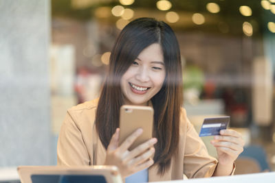 Portrait of a smiling young woman using mobile phone