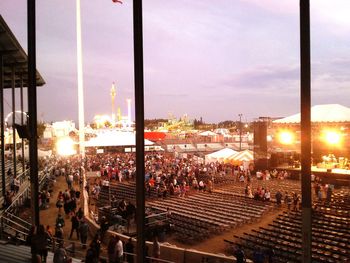 Crowd in city against sky during sunset