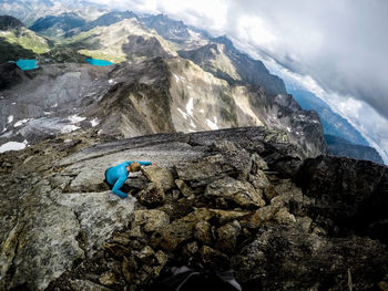 High angle view of man on rocks by mountains against sky