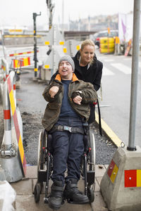 Caretaker pushing disabled man on wheelchair outdoors