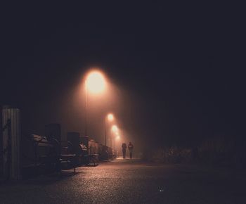 Illuminated empty road against sky at night