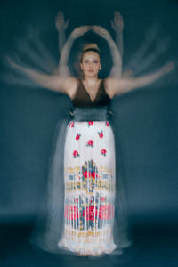 Blurred motion of woman dancing against gray background