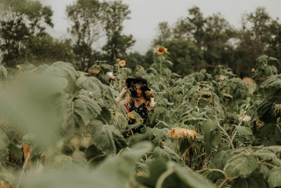 Young woman standing amidst sunflowers on field