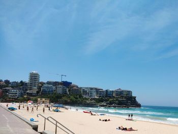 People at beach against blue sky