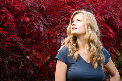 Portrait of beautiful smiling young woman in autumn park with japanese maple tree on a background
