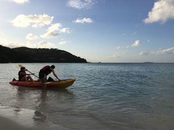 People in sea against sky