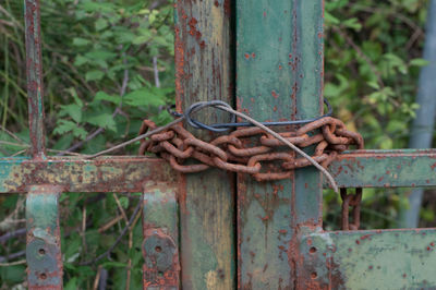 Close-up of rusty chain tied up on metal fence