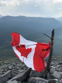 Red flag on rock against sky