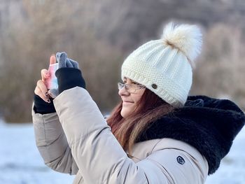 Woman photographing with mobile phone during winter