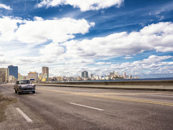 Cars on road in city against sky