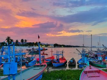 Boats moored at harbor during sunset