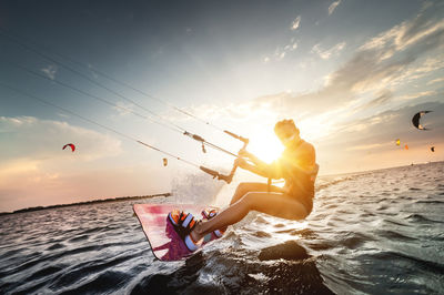 Woman kitesurfing against sky during sunset