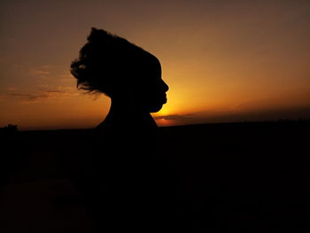 Silhouette woman against orange sky during sunset