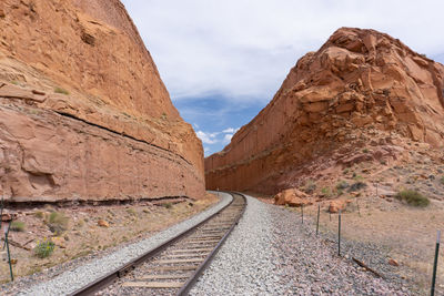 Railroad track amidst rock formation against sky
