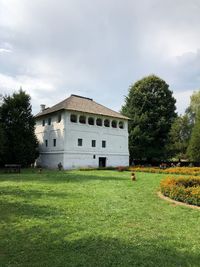 House on field by lawn against sky