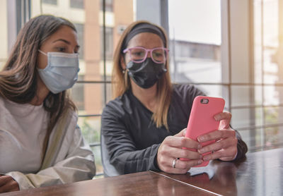 Two casual relaxed girls sitting together checking a mobile phone