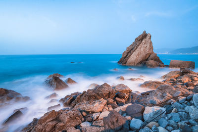 Rocks on beach against blue sky